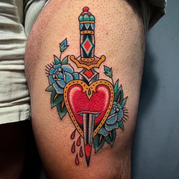 A dagger through a heart with blue roses tattoo