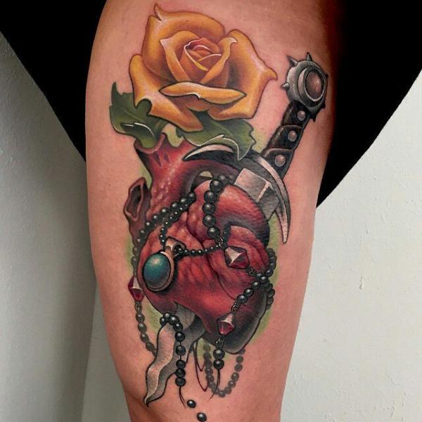 A dagger through a human heart with yellow rose tattoo