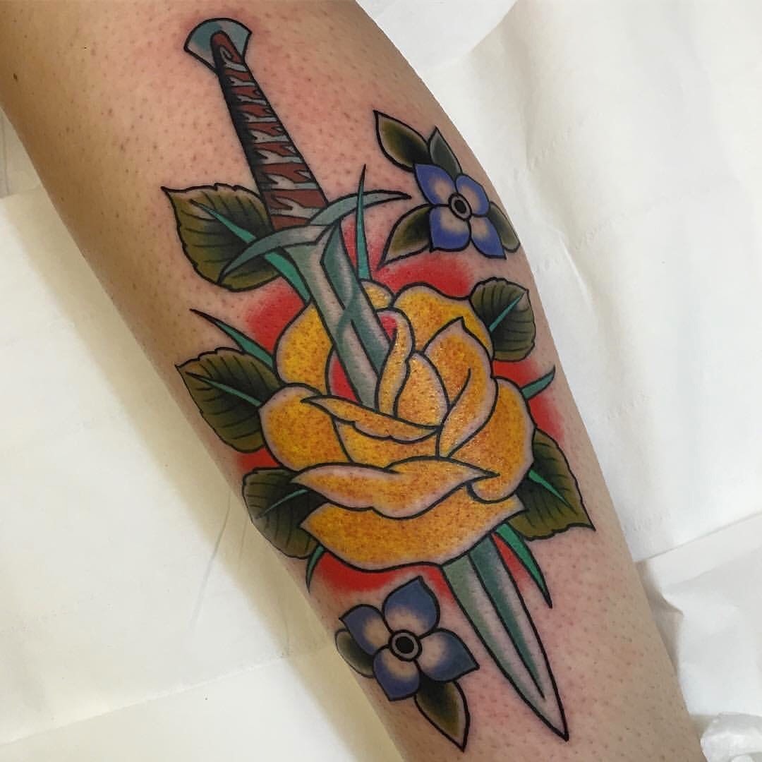 A dagger through a yellow rose