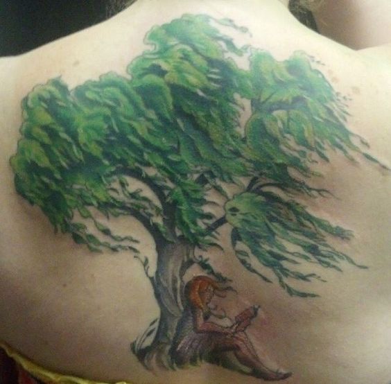 A woman sitting at a willow tree back tattoo