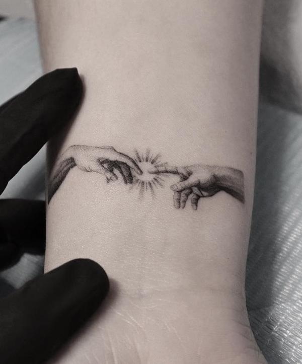 Adam hands and sun tattoo