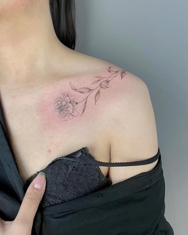 Black and grey marigold clavicle tattoo