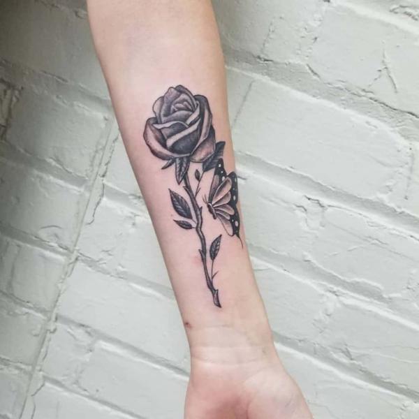 Black and grey rose with stem and butterfly tattoo forearm