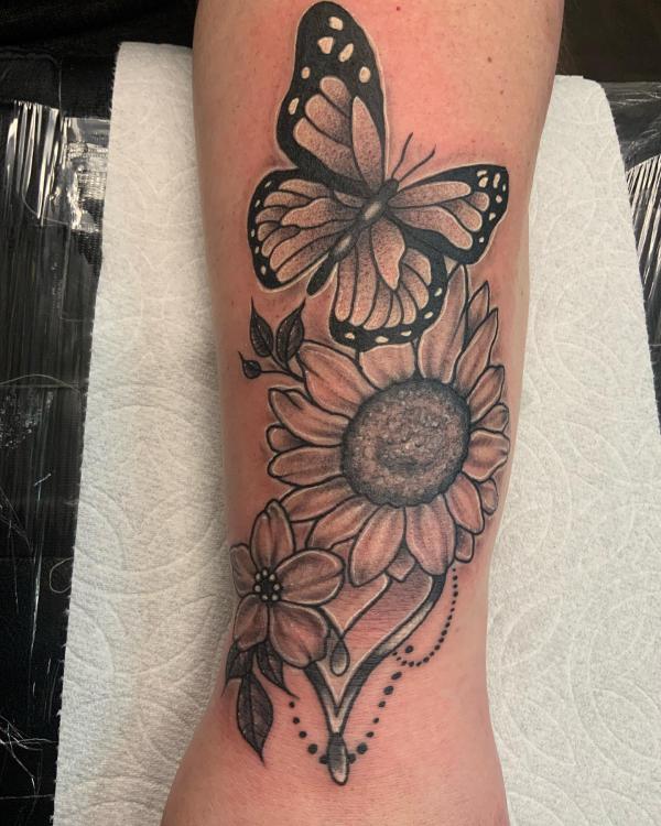 Black and grey sunflower and butterfly forearm tattoo