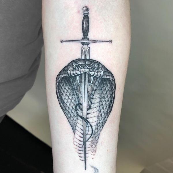 Black and grey sword pierced cobra head tattoo