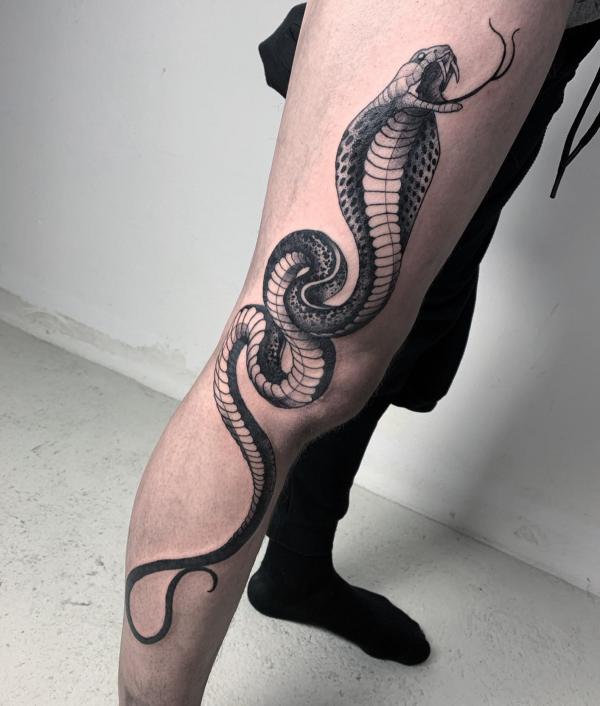 Black and white cobra tattoo on the side of leg