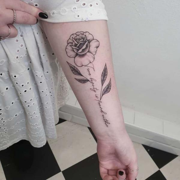 Black and white rose tattoo with quote as stem True beauty is found within