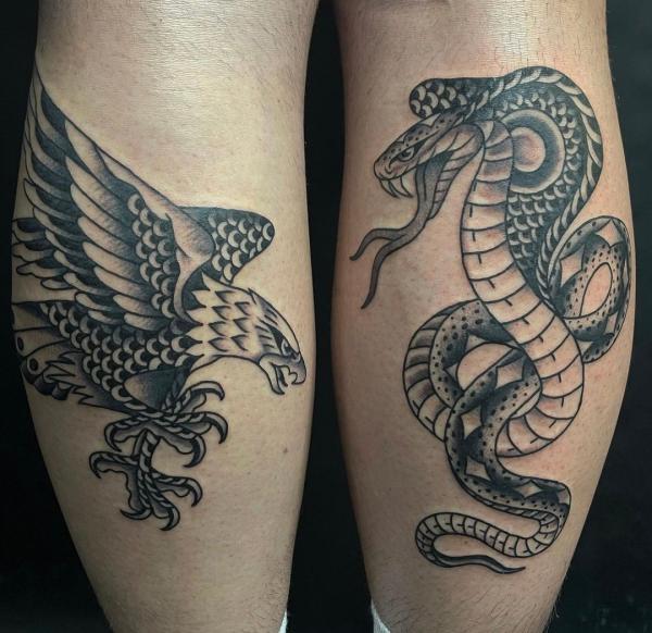 Black and white traditional cobra and eagle tattoo on each of calfs