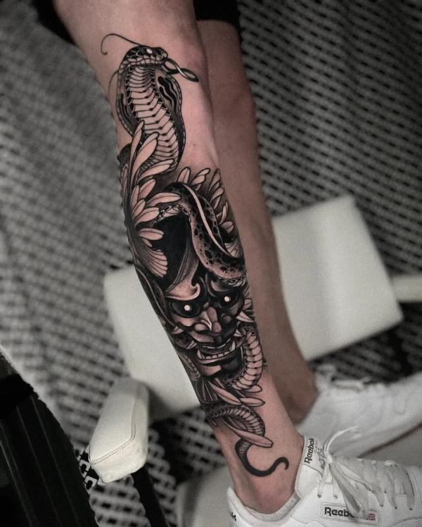 Blackwork cobra and demon lower leg tattoo