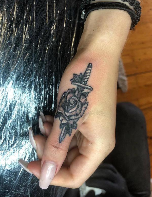 Blackwork rose and dagger finger tattoo