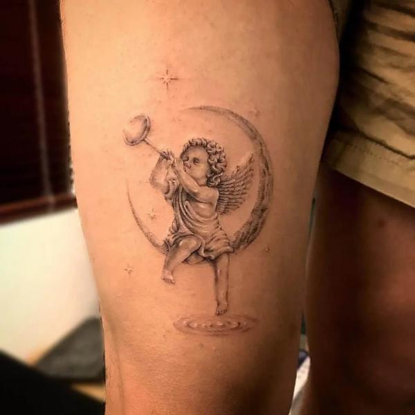 Cherub blowing trumpet sitting on crescent moon tattoo