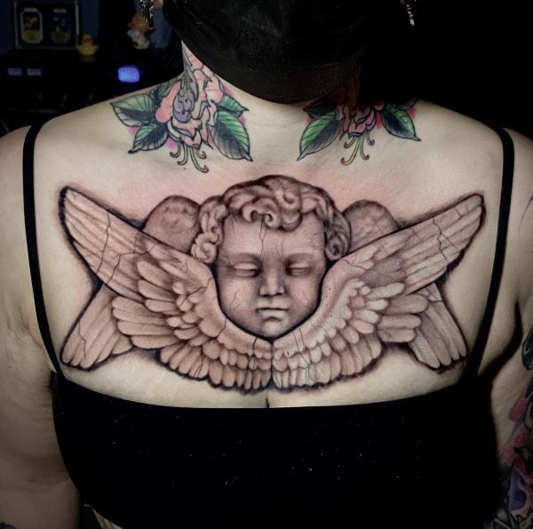 Cherub face with wings chest tattoo