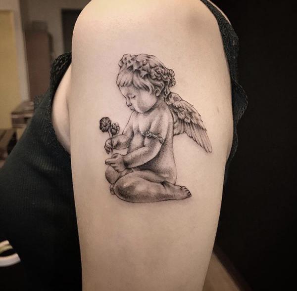 Cute cherub with flower arm tattoo