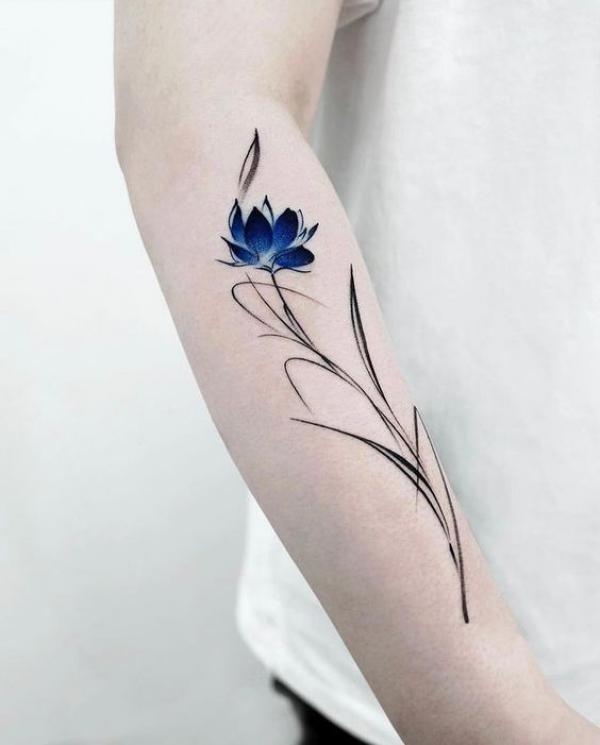 Dainty blue lotus tattoo on forearm