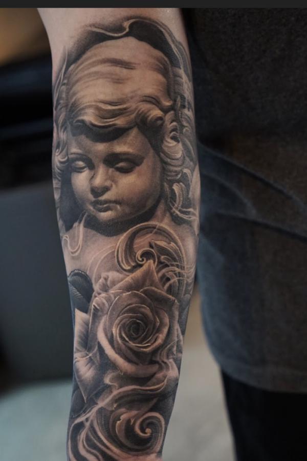 Dark cherub and roses forearm tattoo