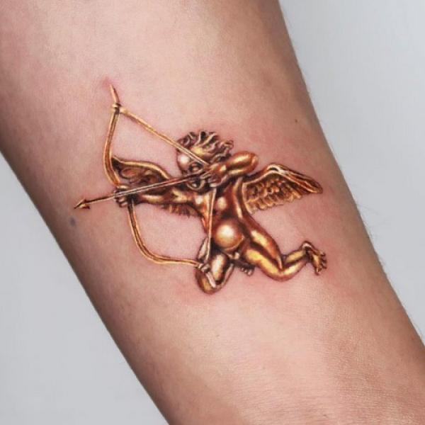 Golden cupid cherub tattoo on arm