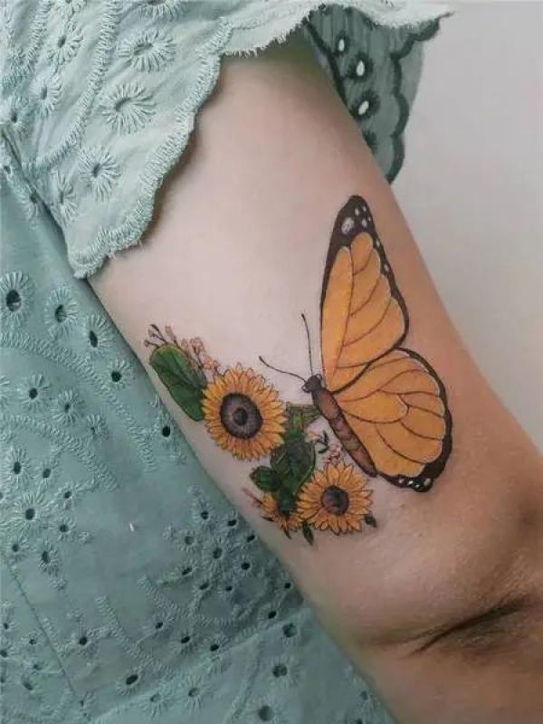 Half butterfly half sunflowers tattoo above elbow