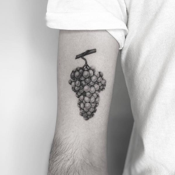 Hanging bunch of grapes bicep tattoo black and grey