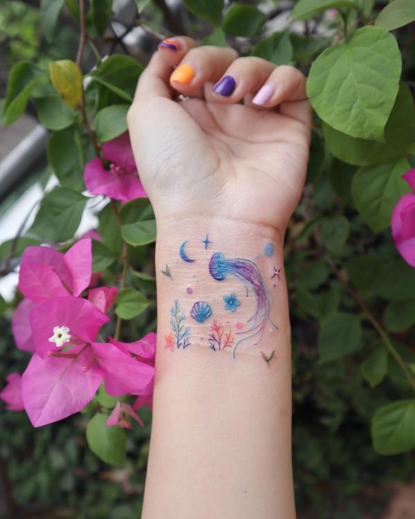 Jellyfish and shell with moon and stars tattoo on wrist