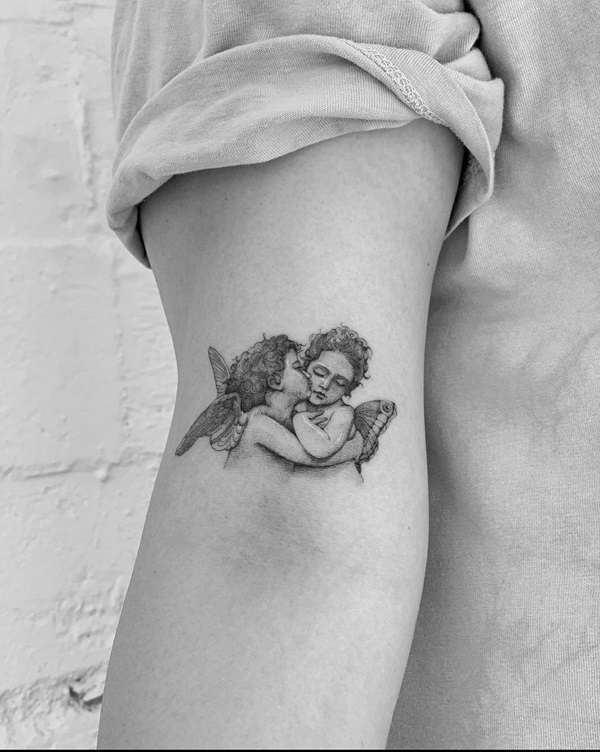 Kissing cherub above elbow tattoo black and grey