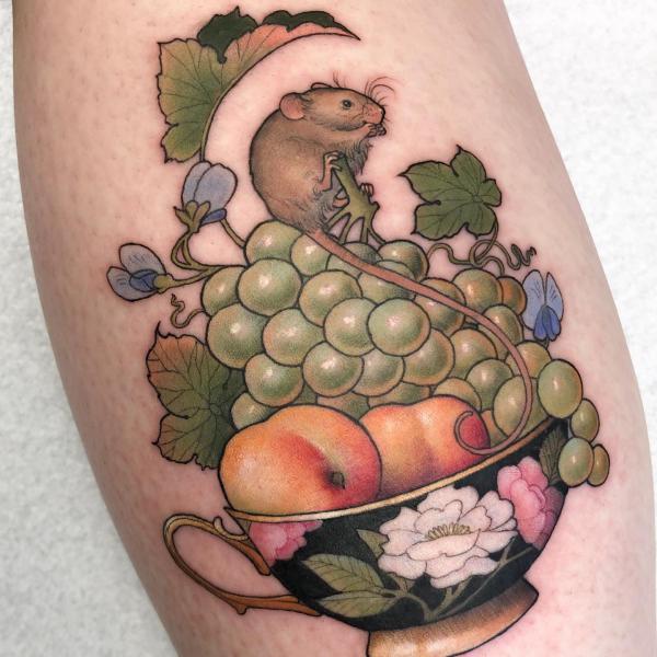 Neo traditional tattoo of a mouse on grapes and apple in a bowl