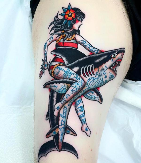 Pinup girl riding a shark tattoo traditional style