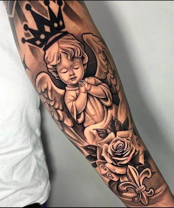Praying cherub with crown and rose forearm tattoo