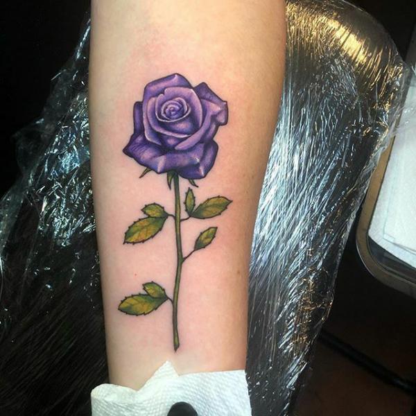 Single purple rose with stem tattoo forearm