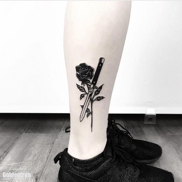Small black rose and dagger tattoo