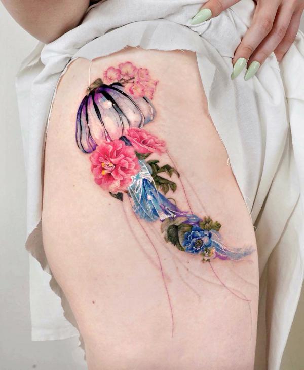 Stylized jellyfish and flowers thigh tattoo