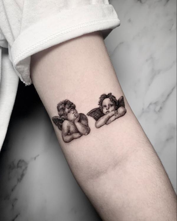 Two cherubs tattoo above inner elbow tattoo