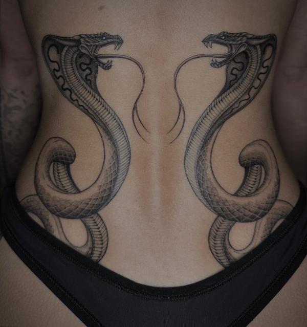 Two symmetrical cobras lower back tattoo