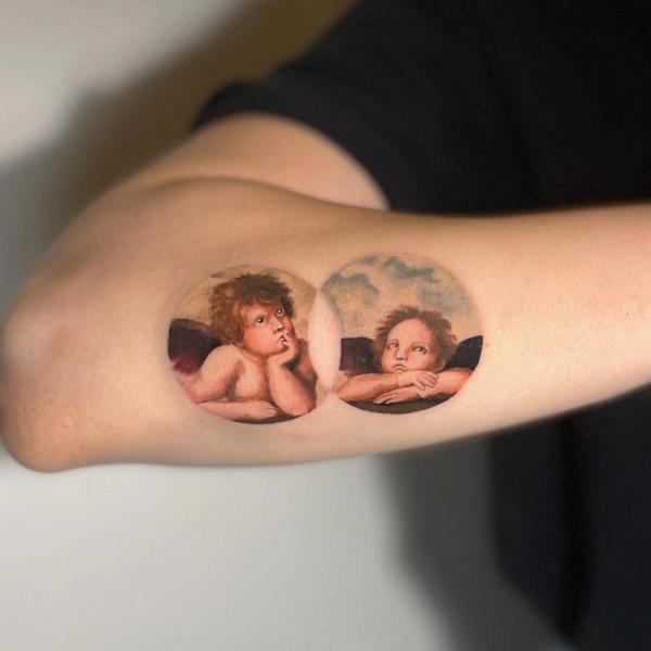 Two thinking cherubs forearm tattoo