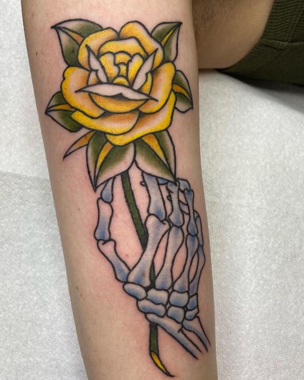 Yellow rose and skeleton hand tattoo