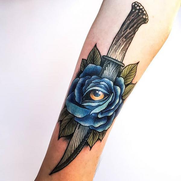 wooden dagger pierced a blue rose with an eye tattoo