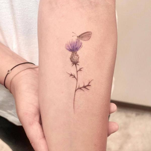A butterfly perched on a thistle tattoo