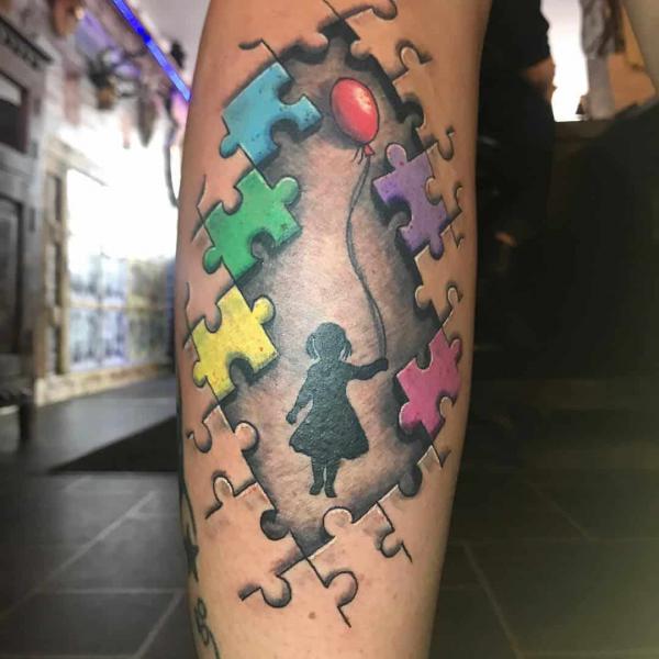 A girl holding balloon in puzzle pieces tattoo