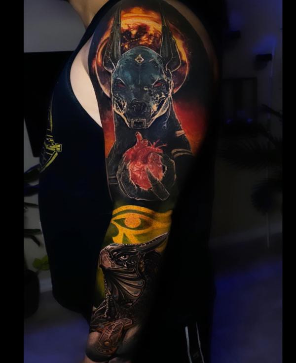 Anubis holding a human heart and Eye of Horus tattoo