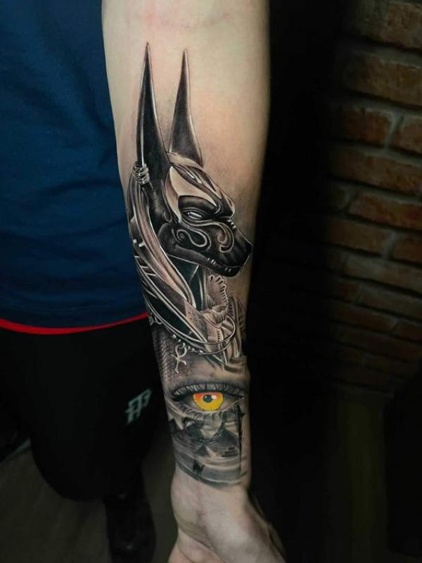 Anubis with eye of Horus tattoo on forearm