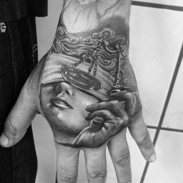 Black and grey Lady with Scales of justice hand tattoo