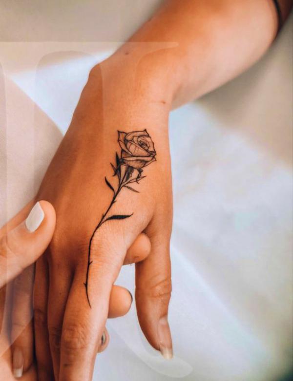 Black and grey rose tattoo on upper index finger