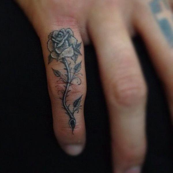 Black and grey rose with thorns tattoo on ring finger