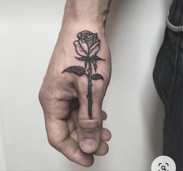 Black and grey rose with thorns tattoo on thumb
