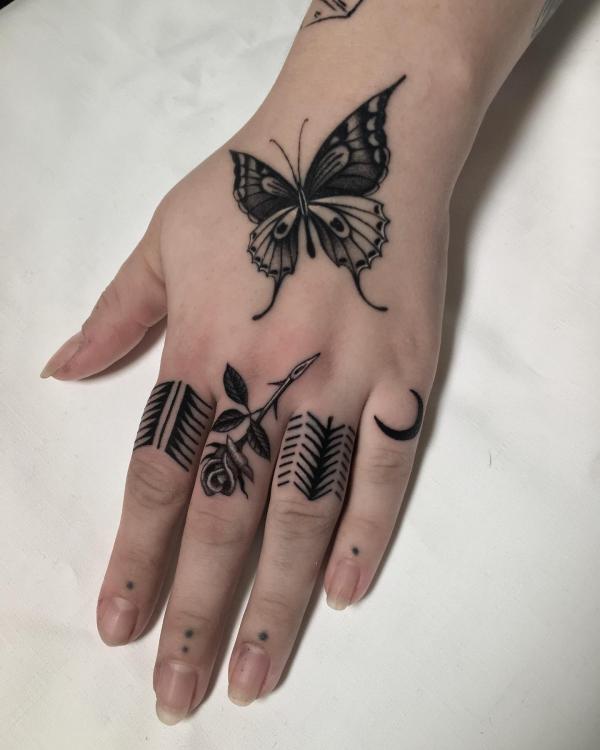 Black and white rose tattoo on middle finger