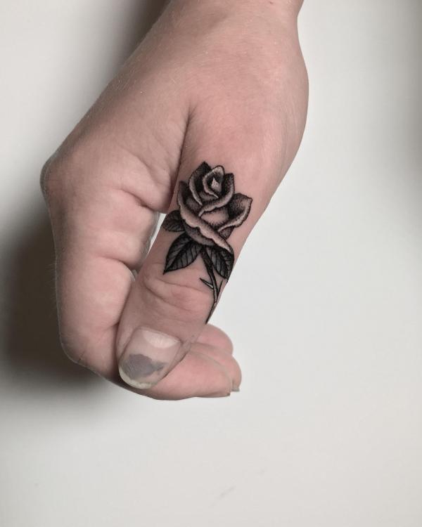Black and white rose tattoo on thumb