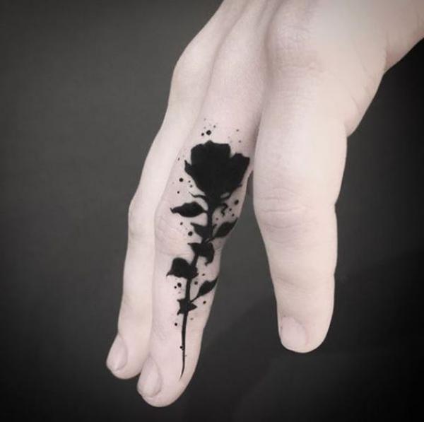 Black ink rose tattoo on the side of finger