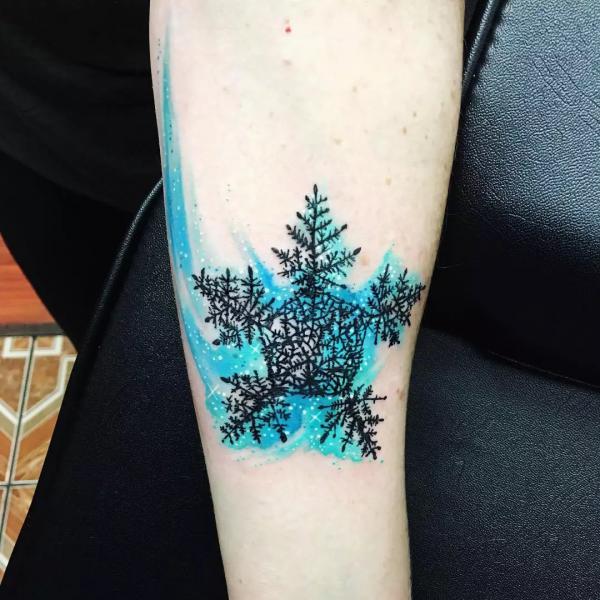Black snowflake on blue watercolor backdrop tattoo
