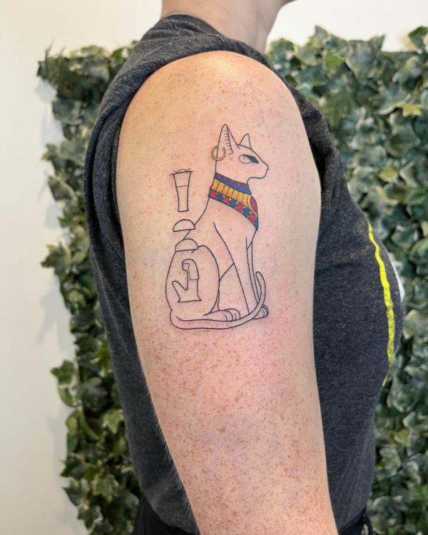 Fine line Bastet upper arm tattoo