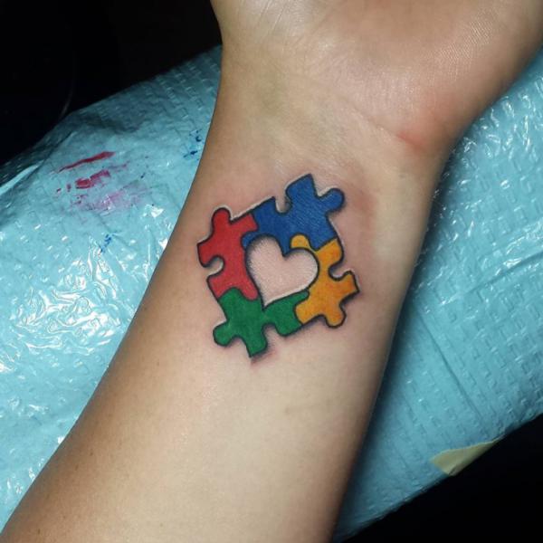 Four Puzzle Pieces forming a love symbol wrist tattoo