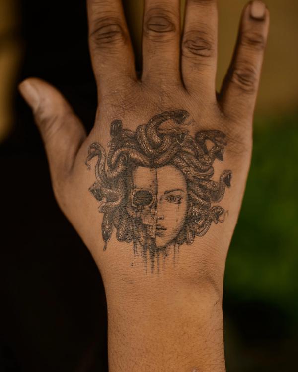 Half skull and half Medusa hand tattoo